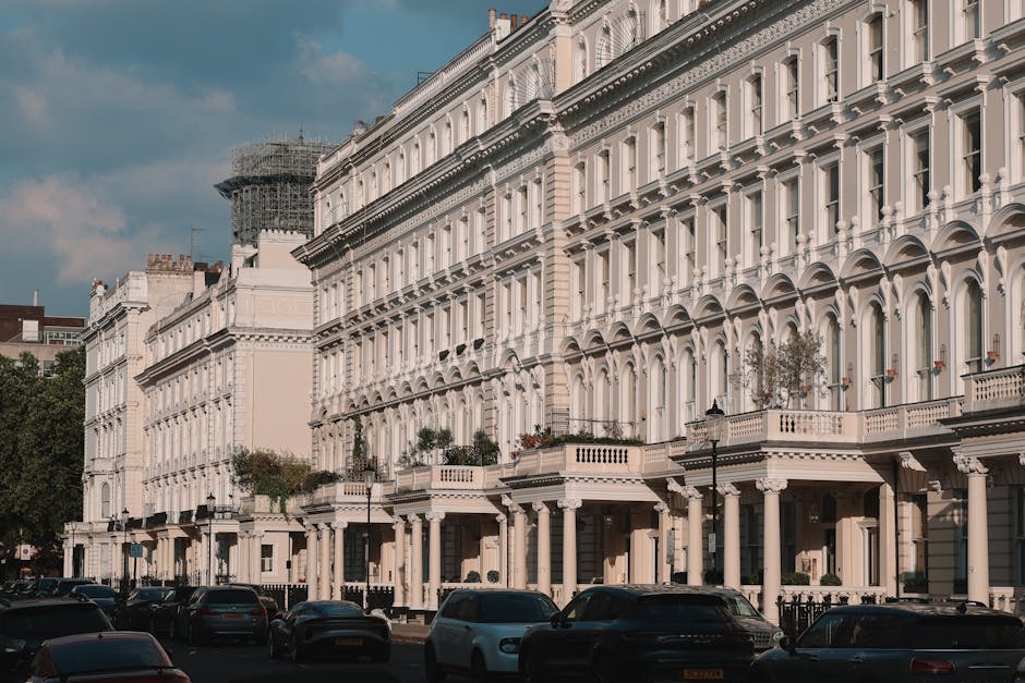 A quiet residential street in Earls Court with traditional Victorian terraced houses featuring decorative mouldings, bay windows, and brick facades painted in white and neutral tones. The pavement is 